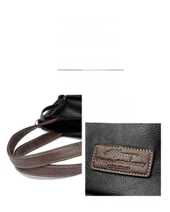 Detailansicht der schwarzen Litschi-Leder-Tasche mit braun genähten Griffen im Kontrast