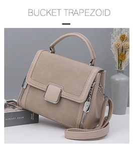 Detail of beige trapezoid handbag featuring silver square buckle and textured leather finish