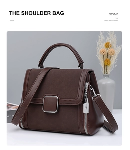 Detail of dark brown tote bag with metallic buckle and silver chain pendant