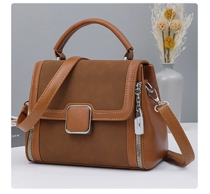 Close-up of brown patchwork handbag featuring suede flap and metallic side zipper detail