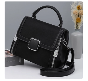 Detail of black matte leather handbag with silver square buckle and decorative side zippers