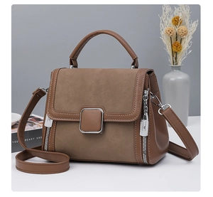 Detail of brown leather and suede panel handbag with square silver buckle and zipper