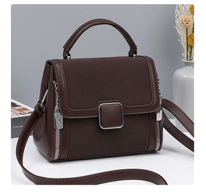Detailed view of dark coffee leather handbag with top handle and silver side zipper decoration