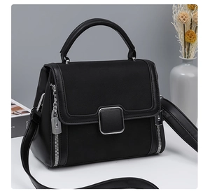 Detail of a black crossbody bag showing textured leather patches and a silver square lock