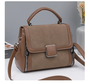 Close-up of brown textured leather and suede handbag with metallic buckle and zipper details