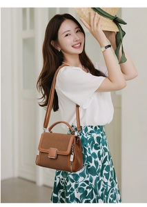 Brown faux leather handbag with silver buckle detail shown on a model in a stylish setting