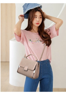 Detail view of stylish beige leather handbag with metal zippers and crossbody strap