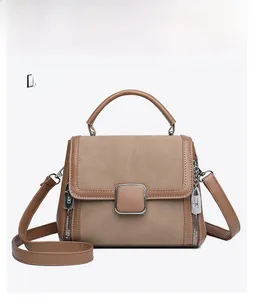 Detail of khaki leather handbag featuring square metal buckle and zipper lock accents