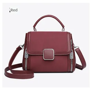 Close-up of burgundy leather handbag with square metal buckle and side zipper details