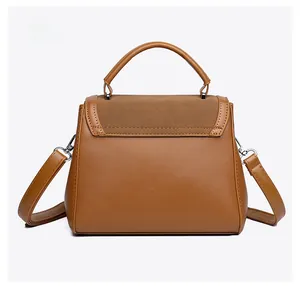Back view of a tan faux leather handbag with suede flap and detachable shoulder strap