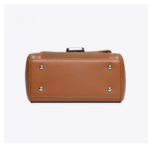 Detailed bottom view of brown leather handbag featuring four silver metal feet and neat stitching