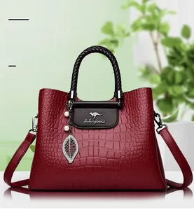 Détail du sac à main rouge motif crocodile avec breloque perle et poignée tressée