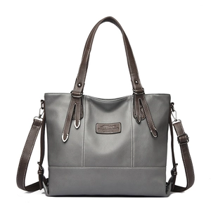 Grey leather tote bag with brown handles and contrast stitching on a white background