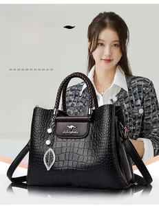 Gros plan du sac à main noir texture croco avec poignée tressée et pendentif perle