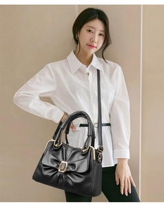 Detail of elegant black pleated handbag with gold square buckle and adjustable strap