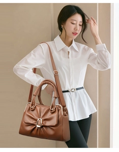 Detailed view of brown pleated handbag with golden buckle on model for styling