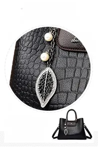 Détail du sac à main en cuir embossé noir avec pendentif feuille et décoration perle