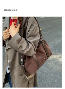 Detail view of brown suede tote bag featuring a leather handle and woven shoulder strap