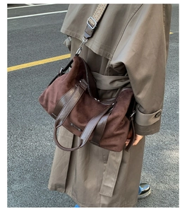 Detail of a large brown faux suede tote bag with leather straps and metal side buckles