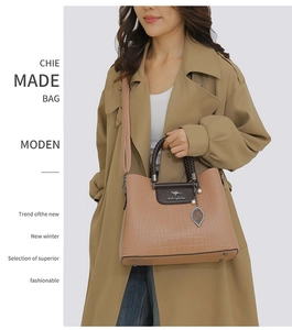 Détail d'un sac à main gaufré camel avec poignée tressée et charm feuille de perles