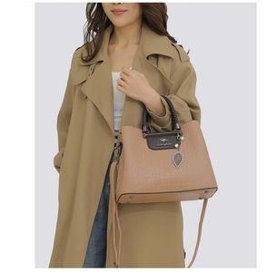 Détail du sac à main marron à motif crocodile avec poignée tressée et pendentif feuille