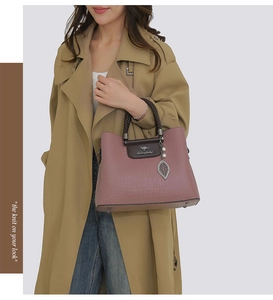 Détail du sac à main en cuir gaufré mauve avec poignée tissée et breloque perle