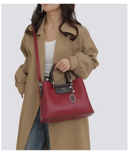 Détail du sac cabas rouge gaufré avec poignées tressées et pendentif feuille en métal