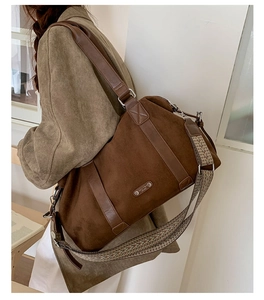 Detailed view of brown suede tote bag featuring a decorative woven strap and metal logo