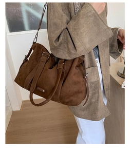 Detail of large brown suede tote bag with leather handles and metal buckle on side