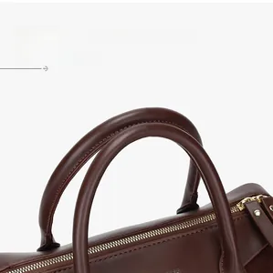 Macro shot of durable leather handles and gold metal zipper on dark brown Boston bag