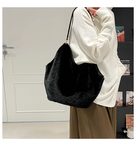 Close-up of fluffy black faux fur tote bag with slim leather handles for winter