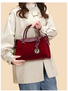 Detail of burgundy Boston handbag showing mixed matte leather texture and F metal pendant