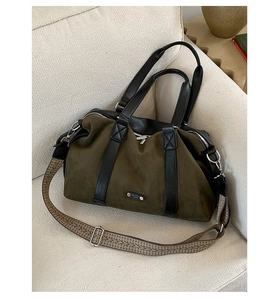 Detail of olive green suede tote bag with black leather handles and woven shoulder strap
