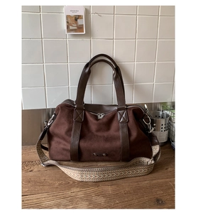 Detail of dark brown faux suede tote with a geometric jacquard woven strap on wood surface