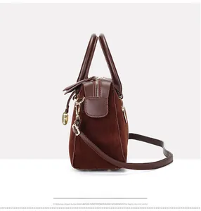 Detail view of large brown Boston bag with smooth leather handles and gold F-pendant charm