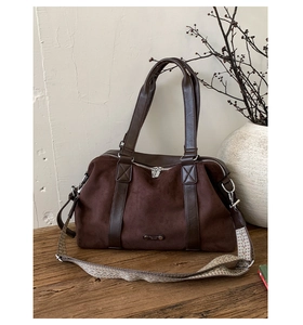 Detail of dark brown suede tote with ethnic style woven strap and metallic hardware