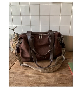 Close-up of deep brown suede tote with textured woven strap on a wooden surface