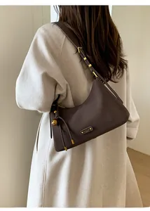 Close-up of a vintage brown underarm bag with gold ball charm on a wool coat