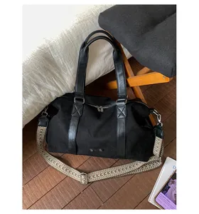 Detail of black suede tote bag featuring metallic logo and adjustable chevron strap