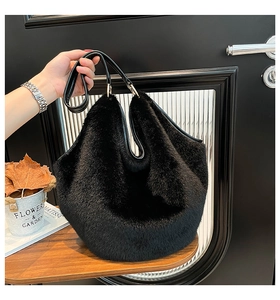 Detail of black faux fur tote bag with leather handles and gold hardware held by a person