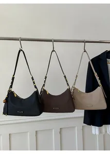 Three minimalist underarm bags in black, brown, and beige displayed on a metal rod