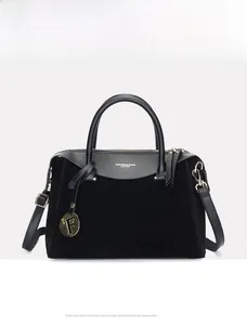 Detail of black suede and leather Boston bag featuring gold ring pendant and logo