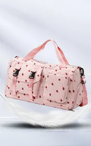Detail view of pink strawberry travel bag with light fabric texture and buckles