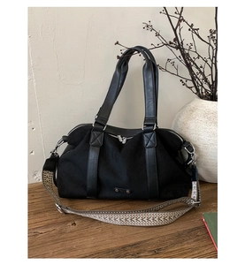 Close-up of black canvas tote bag with leather trim and ethnic style woven strap