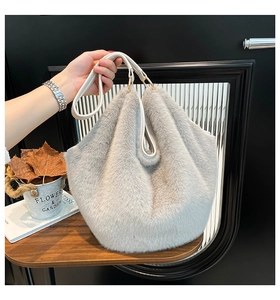 Detail of grey plush faux fur tote bag with white leather handle and gold hardware