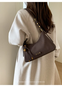 Detail of vintage hobo bag featuring gold hardware and drawstring on matte dark brown leather