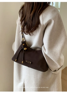 Close-up of brown suede hobo bag with gold bead accents and minimalist branding