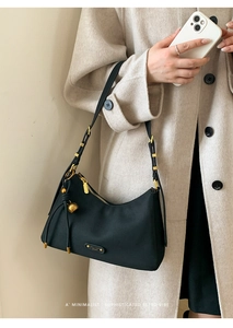 Close-up of black crescent shoulder bag with golden hardware and knot detail
