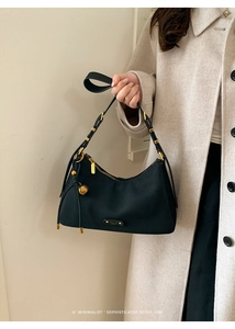 Detail of black crescent hobo bag featuring gold shell charm and textured fabric finish