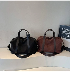Detalle de bolsos tote grandes de lona negra y marrón con asas de cuero en un expositor